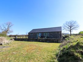 A stone cottage with a slate roof and fenced patio in a grassy area with trees at Cwtch in Swyddffynnon near Pontrhydfendigaid