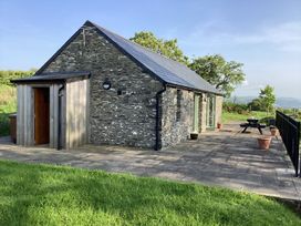 A stone cottage with slate roof and patio with picnic table and potted plants at Cwtch in Swyddffynnon near Pontrhydfendigaid
