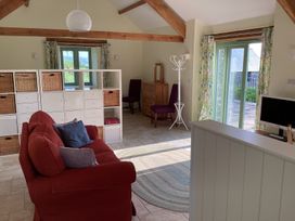 A living room with a red sofa and storage shelves near windows and sliding glass door at Cwtch in Swyddffynnon near Pontrhydfendigaid