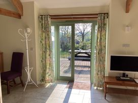 A room with glass doors leading to a patio table outside with floral curtains a coat stand a chair and a table with a monitor at Cwtch in Swyddffynnon near Pontrhydfendigaid