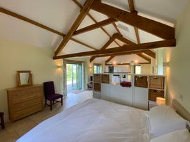 A bedroom with wooden beams and storage units that separate the kitchen area at Cwtch in Swyddffynnon near Pontrhydfendigaid