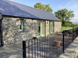A stone building with green framed windows and doors a black metal fence and outdoor furniture at Cwtch in Swyddffynnon near Pontrhydfendigaid