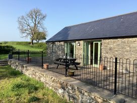 A stone building with green doors and windows and a patio with black metal fencing and a picnic table at Cwtch in Swyddffynnon near Pontrhydfendigaid