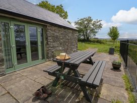 An outdoor seating area with a stone wall and green doors at Cwtch in Swyddffynnon near Pontrhydfendigaid