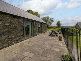 An outdoor area with a stone wall, patio seating and planters at Cwtch in Swyddffynnon near Pontrhydfendigaid