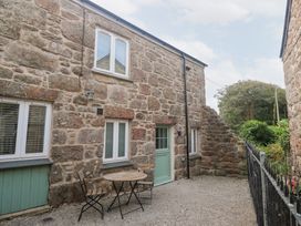 An outdoor area with a stone wall, table and chairs at Mys Hedra Farm St Buryan