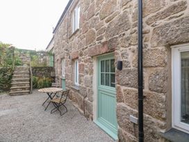An outdoor area with a table and chair near stone walls at Mys Hedra Farm in St Buryan
