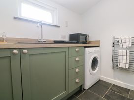 A utility room with a washing machine and microwave at Mys Hedra Farm St Buryan