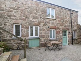 An outdoor area with a stone wall and a table with chairs at Mys Hedra Farm St Buryan