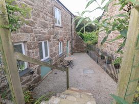 An outdoor area with a stone building and a table with chairs at Mys Hedra Farm St Buryan