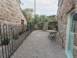 An outdoor area with stone walls, gravel, a table and chairs at Mys Hedra Farm St Buryan