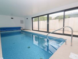 An indoor pool with blue tiles and a stair rail at Mys Hedra Farm St Buryan
