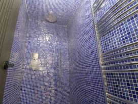 A shower with blue tiled walls and a towel rail at Mys Hedra Farm in St Buryan