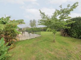 A garden with a tree, lawn, and a fence at Mys Hedra Farm in St Buryan