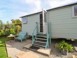 A shepherd's hut with steps leading up to the door and a table with a bench at Higher Merther Farm Shepherds Hut in Helston