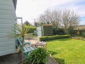 A garden with a plant, bench, and shed at Higher Merther Farm Shepherds Hut in Helston