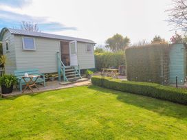 A garden with a shepherd's hut and seating at Higher Merther Farm Shepherds Hut in Helston