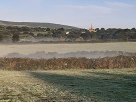 A landscape with a misty field and buildings in the background at Higher Merther Farm Shepherds Hut Sithney near Helston