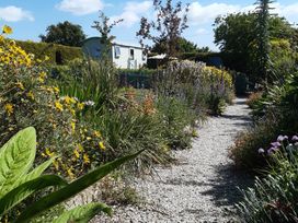 A garden with a gravel path and flowers at Higher Merther Farm Shepherds Hut in Sithney near Helston