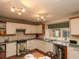 A kitchen with white cabinets a stove a sink and a window with a green blind at Bellmanear Farm Cottage North Grimston near Malton