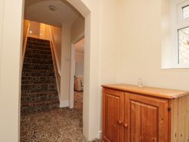 Hallway with patterned carpeted stairs wooden cabinet and a window at Bellmanear Farm Cottage North Grimston near Malton