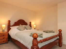 A bedroom with a wooden bed frame two bedside tables with lamps and folded towels on the bed at Bellmanear Farm Cottage in North Grimston near Malton