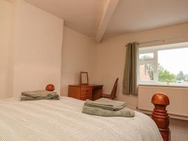 A bedroom with a wooden bed and folded towels on it a wooden desk and chair near a window with green curtains at Bellmanear Farm Cottage North Grimston near Malton