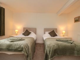 A bedroom with two single beds with green blankets and pillows at Bellmanear Farm Cottage in North Grimston near Malton
