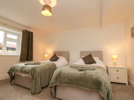 A bedroom with two single beds side by side with green throws pillows and towels a bedside table with a lamp and a window at Bellmanear Farm Cottage North Grimston near Malton