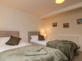 A bedroom with two single beds with green covers and towels and framed pictures on the wall at Bellmanear Farm Cottage North Grimston near Malton