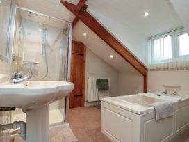 A bathroom with a sink shower and bathtub under a sloped ceiling at Bellmanear Farm Cottage in North Grimston near Malton
