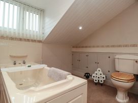 A bathroom with a bathtub a toilet with a wooden seat and a sheep shaped toilet paper holder at Bellmanear Farm Cottage in North Grimston near Malton