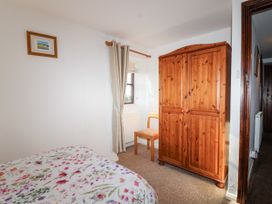 A bedroom with a bed, wardrobe, and chair at The Hayloft in Common Moor near Liskeard