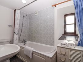 A bathroom with a bathtub, shower, toilet, sink, and towels at The Hayloft in Common Moor near Liskeard