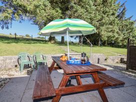 A picnic table with umbrella and chairs at The Hayloft in Common Moor near Liskeard