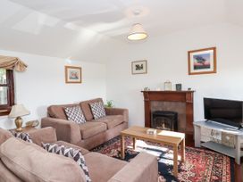 A living room with sofas, a coffee table, and a tv at The Dairy in Common Moor near Liskeard