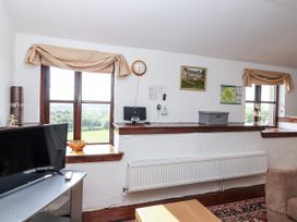 A living room with a television and clock at The Dairy in Common Moor near Liskeard