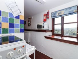 A kitchen with stove and microwave at The Dairy in Common Moor near Liskeard