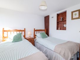 A bedroom with two beds and a bedside table at The Dairy Common Moor near Liskeard