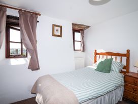 A bedroom with a bed and window at The Dairy in Common Moor near Liskeard