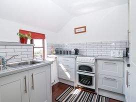A kitchen with sink, window, plant, kettle, and cooker at The Byre Common Moor near Liskeard