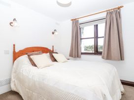 A bedroom with a bed and a window at The Byre in Common Moor near Liskeard