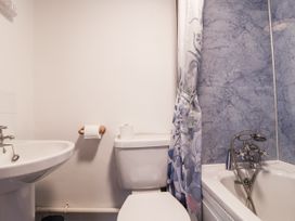 A bathroom featuring a sink, toilet, and bathtub with a shower curtain at The Byre in Common Moor near Liskeard