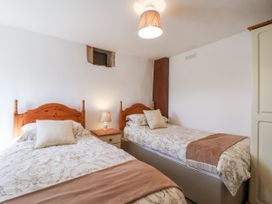 A bedroom with two beds and a nightstand at The Byre Common Moor near Liskeard