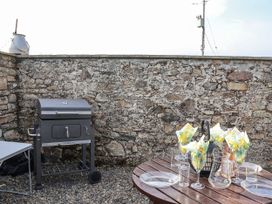 An outdoor area with a grill and a table set with plates and glasses at The Byre in Common Moor near Liskeard