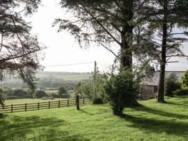 A garden with trees and a house in the background at The Byre Common Moor near Liskeard
