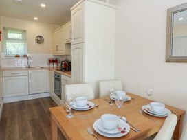A kitchen with white cabinets and a wooden dining table set with plates bowls and glasses at Trem-Yr-Afon in Aberaeron