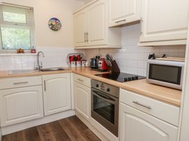 A kitchen with white cabinets a stainless steel oven a microwave a sink and a window at Trem-Yr-Afon in Aberaeron