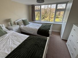 A bedroom with two beds and a wardrobe at Rothay Cottage Ambleside