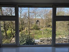 An outdoor view through a window with trees and a building at Rothay Cottage in Ambleside